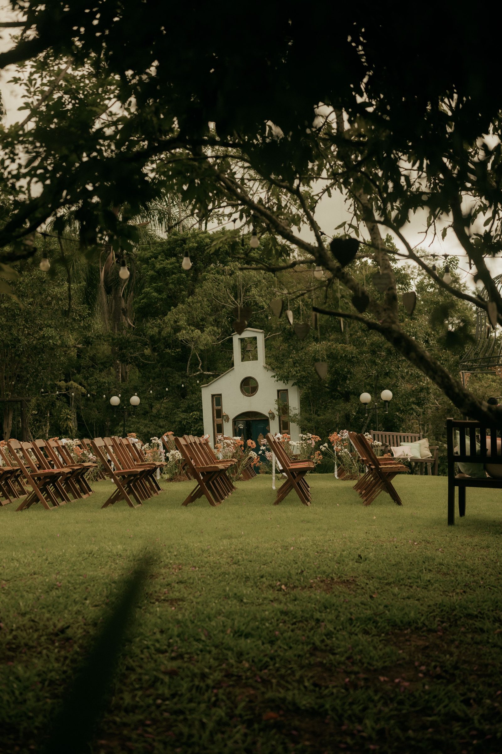 Outdoor wedding ceremony with wooden chairs and floral arrangements